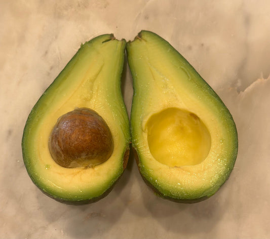 Halved organic Fuerte California avocado on a marble surface